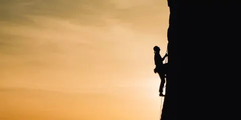 A person climbing up a steep mountain.